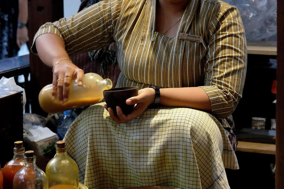 Pekerja di kedai Hamzah Batik menjual jamu untuk diminum dengan harga 3,000 rupiah atau 10,000 rupiah sebotol.