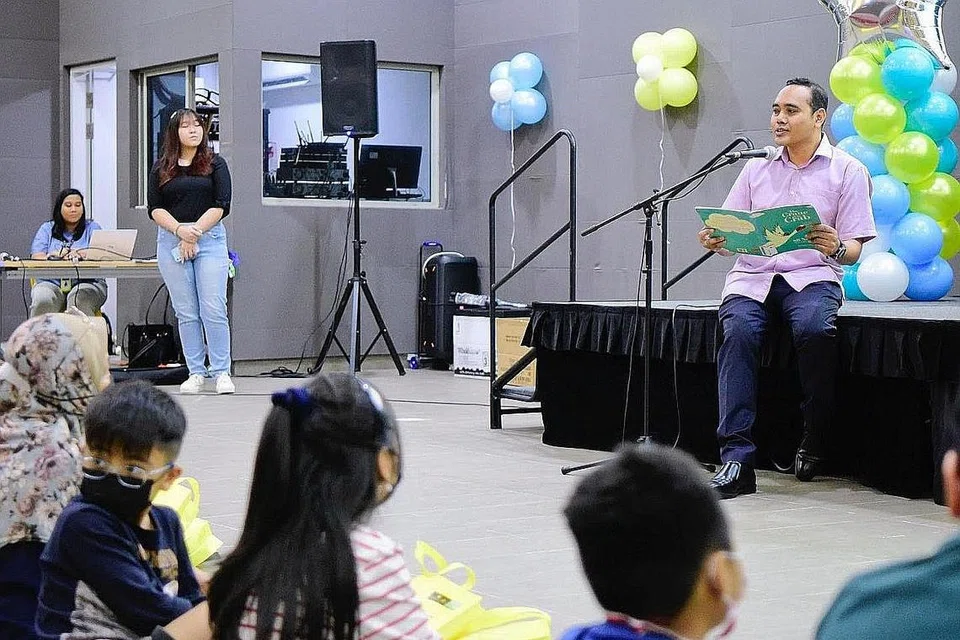 SESI BERCERITA: Encik Zhulkarnain Abdul Rahim membaca buku kepada sekitar 150 ibu bapa dan kanak-kanak pada acara Amazing Read @ Heartlands di M³@Chua Chu Kang. - Foto FACEBOOK ZHULKARNAIN ABDUL RAHIM