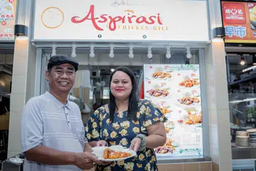 Pengasas Aspirasi Food Galore, Encik Zainnudin Sajat, bersamanya anaknya, Cik Nur’Ain Zainnudin, yang merupakan pemilik generasi kedua syarikat itu, di hadapan gerai terbaru nasi ayam mereka, Aspirasi Chicken Rice, di Vidacity di Pasir Ris.