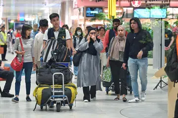 Seorang penumpang lelaki pesawat SQ321 (paling kanan) berjalan keluar dari dewan ketibaan Terminal 2 Lapangan Terbang Changi sekitar 5.30 pagi, disambut anggota keluarganya serta dibantu seorang kakitangan Singapore Airlines (menolak troli).