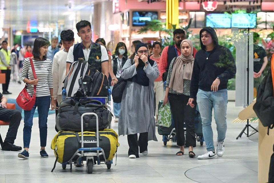 Seorang penumpang lelaki pesawat SQ321 (paling kanan) berjalan keluar dari dewan ketibaan Terminal 2 Lapangan Terbang Changi sekitar 5.30 pagi, disambut anggota keluarganya serta dibantu seorang kakitangan Singapore Airlines (menolak troli).