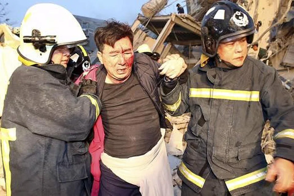 DIBANTU: Anggota penyelamat membantu seorang mangsa gempa bumi berdekatan sebuah bangunan yang rosak teruk di kawasan Tainan. - Foto REUTERS