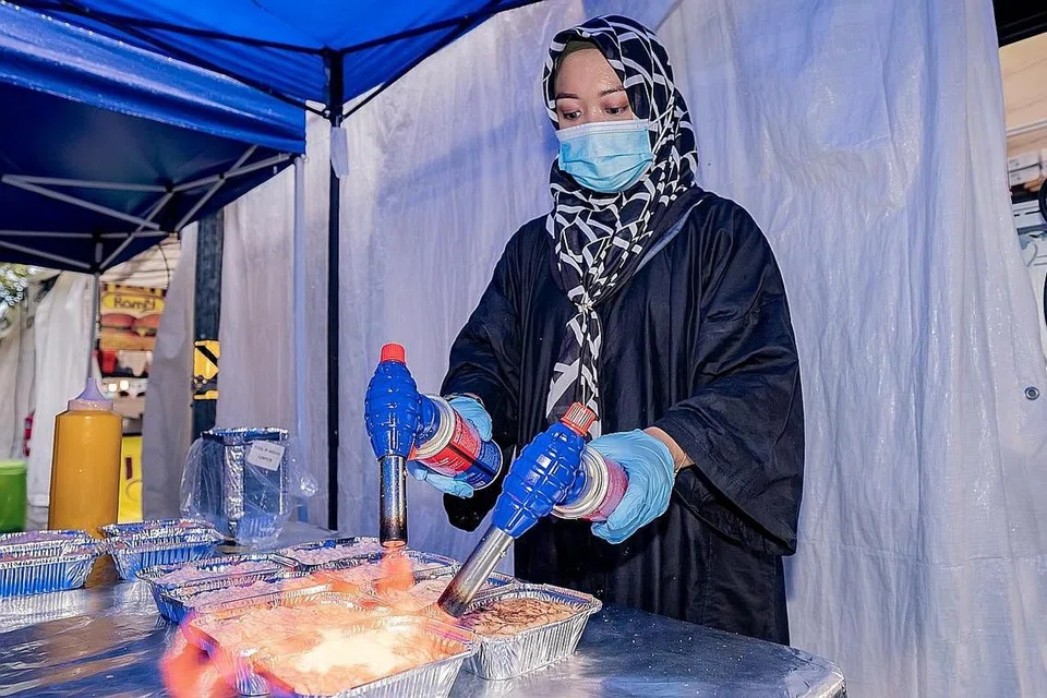 BAKAR SUSHI: Cik Siti Raudah Osman membakar dulang sushi di gerainya di Bazar Kampong Glam untuk dijual kepada pelanggan. - Foto BH oleh NUR DIYANA TAHA