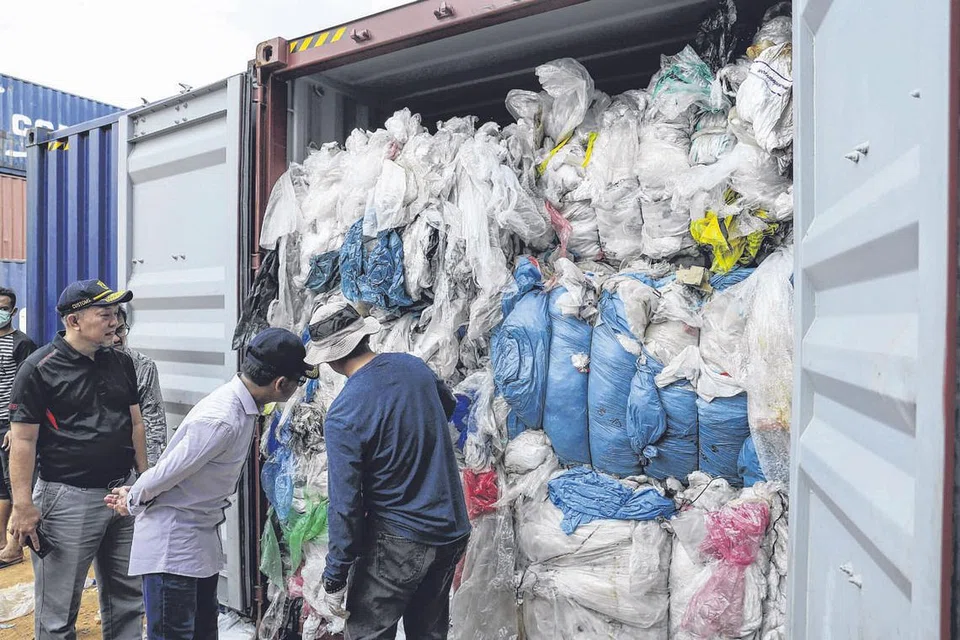 TEMPAT BUANG SAMPAH: Gambar ini diambil pada 15 Jun lalu yang menunjukkan pegawai kastam Indonesia daripada pejabat sekitaran tempatan sedang memerika satu daripada 65 kontena yang mengandungi sampah plastik, di pelabuhan Batu Ampar, Batam. - Foto AFP