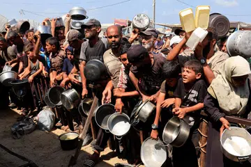 Penduduk Gaza yang dilanda krisis kebuluran, berebut-rebut menantikan giliran bagi mendapatkan bantuan makanan yang diagihkan di dapur amal di Khan Younis, selatan Gaza.