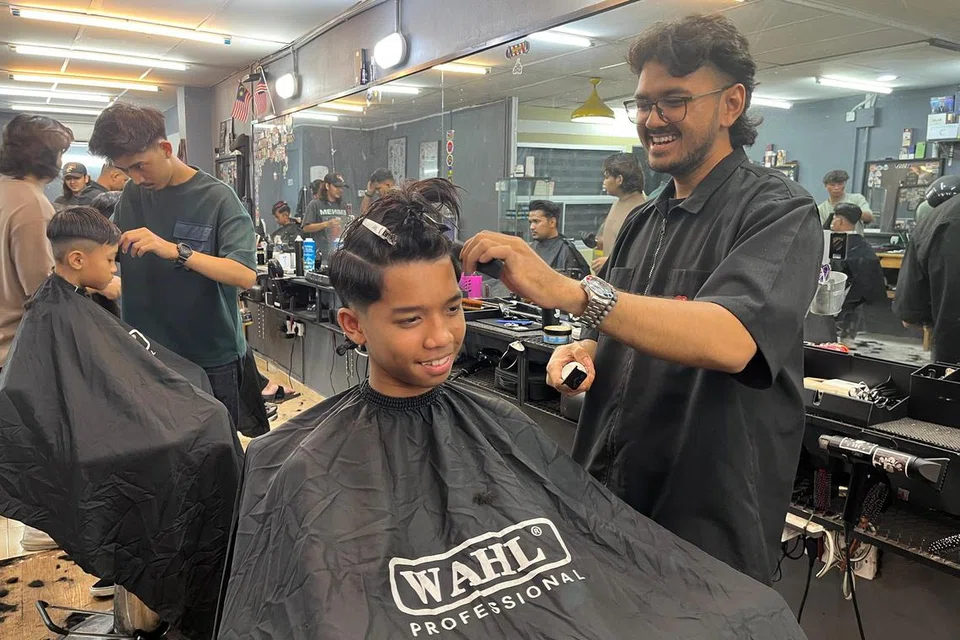 Seorang tukang gunting Gombak Barbers Turf (GBT) di Batu Cave, Encik Ahmad Agus Alfani, merapikan rambut seorang remaja, Muhammad Dzulkarnain Shah Amirul Afifi, mengikut gaya terkini.