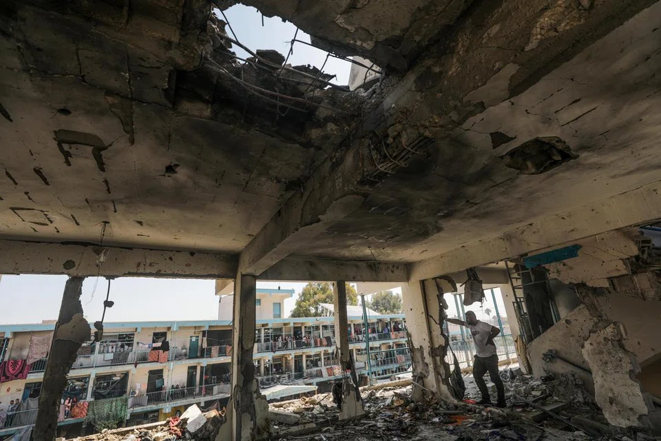 Penduduk Gaza menyaksikan sekolah Agensi Bantuan dan Kerja Menyelamat Pertubuhan Bangsa-Bangsa Bersatu bagi Pelarian Palestin (UNRWA) yang musnah berikutan serangan udara Israel di kem pelarian Al Nusairat di tengah Jaluran Gaza pada 6 Jun.