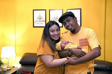 BAYI COMEL: Rahila Rashun bersama bayinya, Maheera Bibi Mohamad Alhaj, yang digendong suami, Mohamad Alhaj, yang lebih dikenali sebagai KP Blavk, seorang 'rapper' setempat. - Foto BM oleh DESMOND FOO