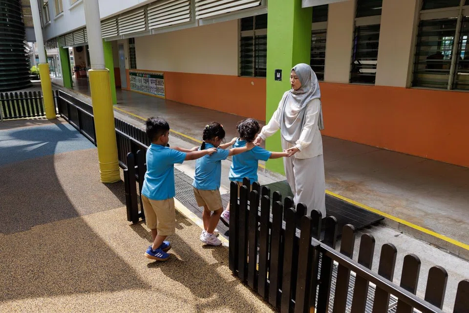 Guru Kanan (Perkembangan Kanak-kanak) Cik Nur Hidayah Mohamed Hisham dari tadika MOE Northoaks, atau MK@Northoaks, membimbing sekumpulan kanak-kanak prasekolah selepas sesi bermain di taman permainan.