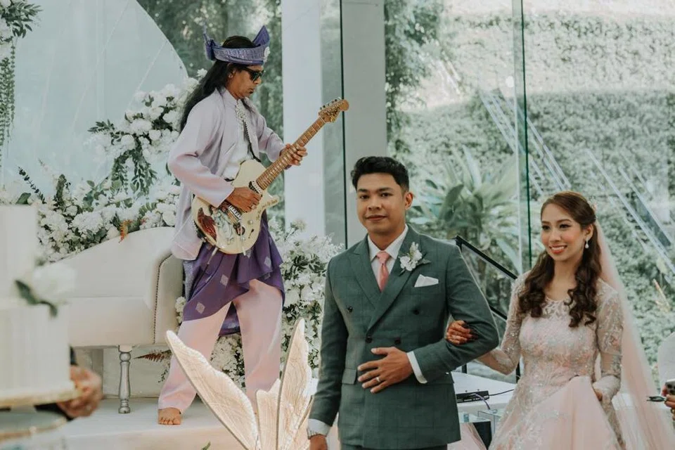 Bapa pengantin perempuan, Shaik Abdul Halim (belakang) memainkan lagu instrumental Young and Beautiful di elektrik gitarnya, permintaan mempelai Cik Diyana Mas Ayu Shaik Abdul Halim (kanan) dan Encik Muhammad Tarmizi Mahat (kiri) semasa majlis perkahwinan mereka pada 1 November di Hotel Furama Riverfront.