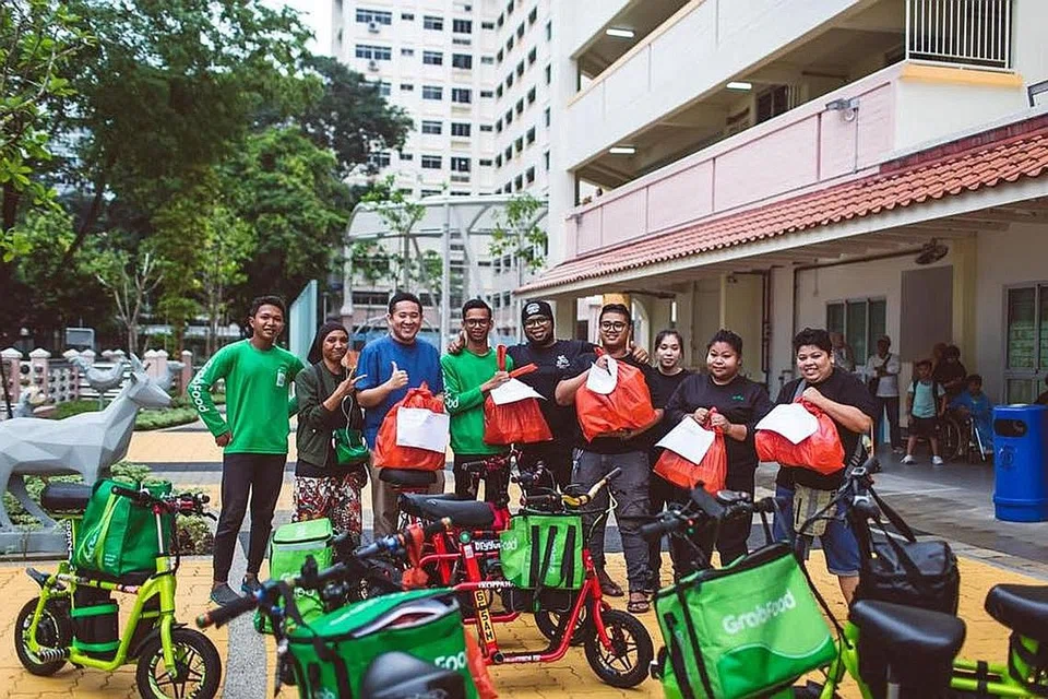 PROJEK AGIH BERIANI: Encik Amrin (gambar kiri) bersama beberapa pengguna PMD yang terlibat dalam projek memberi nasi beriani kepada golongan memerlukan di kawasan Woodlands, Ramadan lalu. - Foto FACEBOOK AMRIN AMIN