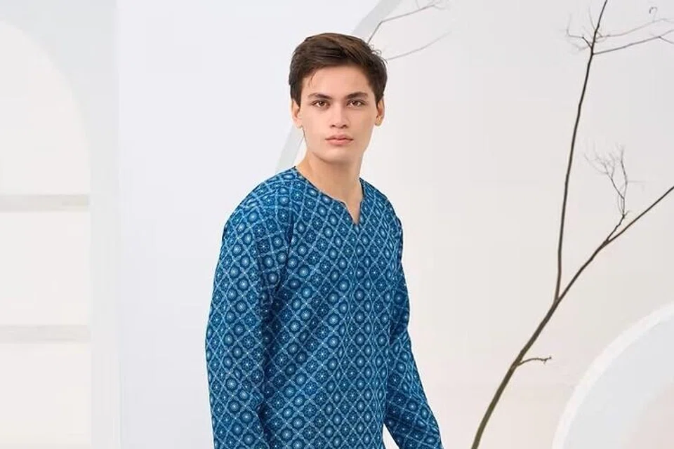Baju Melayu Angkasa 2026 ($80) oleh Minimalist Studio SG direka dengan leher ‘potongan V’ yang tidak mempunyai kolar atau butang. Warna ‘Teal Blue’ merupakan antara pilihan popular pada 2026.  
