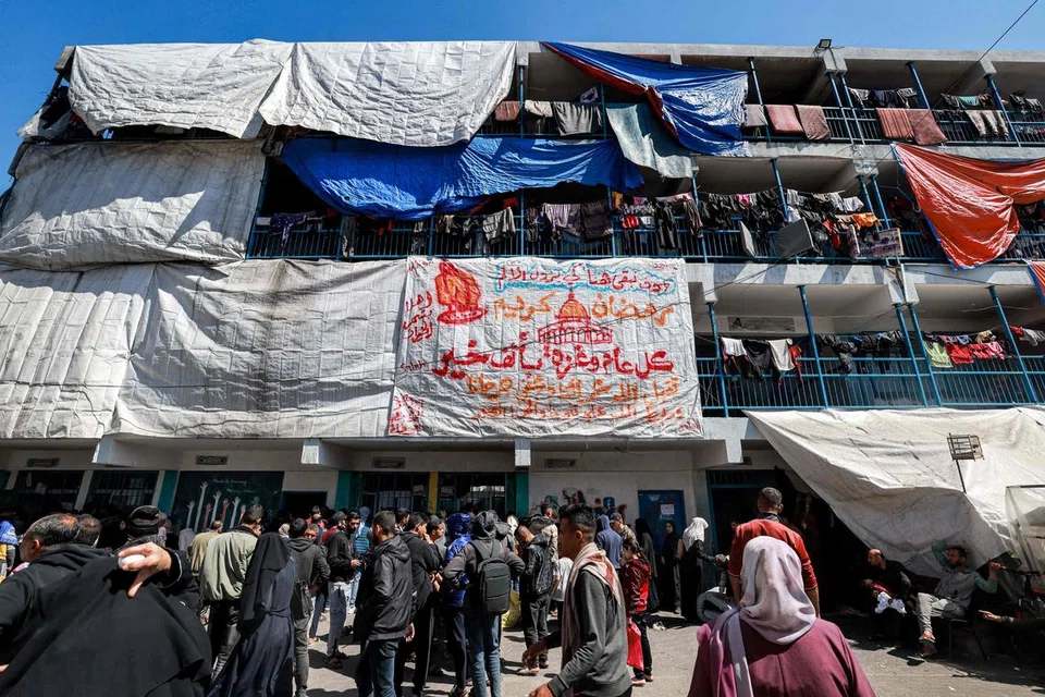 Para penduduk Palestin berkumpul bagi mendapatkan makanan sempena Ramadan yang diagihkan oleh Agensi Bantuan dan Kerja Menyelamat Pertubuhan Bangsa-Bangsa Bersatu (PBB) bagi pelarian Palestin (UNRWA), di Rafah, selatan Gaza, pada 13 Mac.