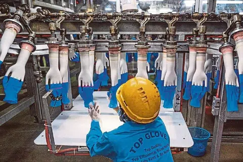 KEPENTINGAN PENGELUAR SARUNG TANGAN: Top Glove menghasilkan 220 juta sarung tangan getah pakai buang setiap hari, Nilai syarikat ini bertambah sekurang-kurangnya enam kali tahun ini (2020) - menjadikannya syarikat tersenarai kedua terbesar di Malaysia - kerana peningkatan permintaan sarung tangan yang banyak sewaktu pandemik ini. Namun, 28 kilangnya terpaksa ditutup beransur-ansur menyusuli peningkatan kes jangkitan Covid-19 dalam kalangan pekerjanya. - Foto AFP