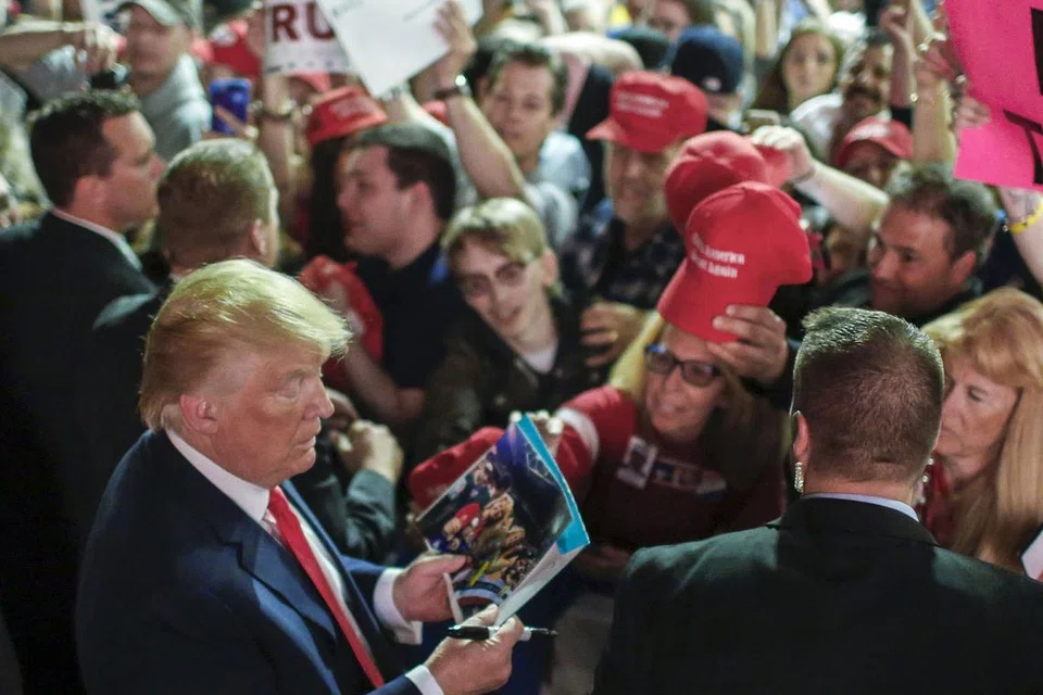 MAHU TANDATANGAN?: Calon Presiden Parti Republikan, Encik Donald Trump, menurunkan tandatangan di foto dan topi selepas bertemu penyokong di perhimpunan di Pusat Sivik Mid-Hudson di Poughkeepsie, New York, semalam. 