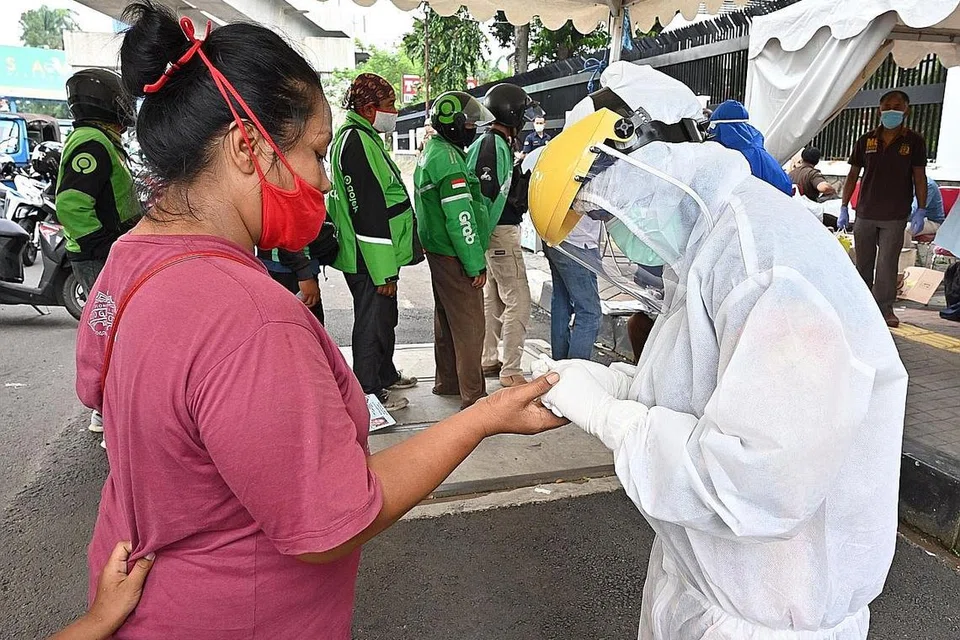 LAKUKAN UJIAN: Seorang jururawat sedang mengambil contoh darah seorang wanita di Jakarta untuk diuji bagi penyakit Covid-19. - Foto AFP