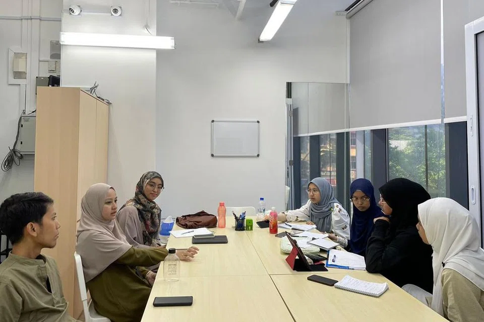 SIBUK BERLATIH: (Dari kiri) Ketua Munazarah SG, Ustaz Muhammad Redha Mohamed Elyas, Penolong Ketua Munazarah SG, Ustazah Sri Wahyu Ahmad; dan pegawai perhubungan Munazarah SG, Ustazah Nur Jannah Mustakim kelihatan melatih pasukan dari Madrasah Alsagoff (kanan) bagi pertandingan debat antarabangsa di Qatar pada 2-4 September.
