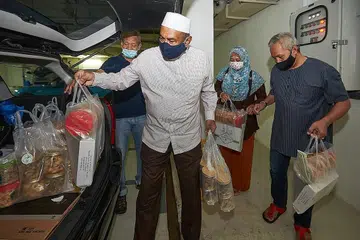 BERSIAP UNTUK PENGHANTARAN: Encik Allaudin (kopiah putih), mantan pengerusi MCS, Encik Rujok Pandi (kiri), dan dua sukarelawan memasukkan beg plastik habuan dan kuih-muih ke dalam kereta untuk dihantar ke rumah keluarga bekas pesalah dalam program 'Ramadan Cheers' yang bermula di Bangunan Hexacube pada 25 April lalu. - Foto BH oleh ROSLEE ABDUL RAZAK