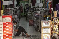 TUNGGU PELANGGAN: Seorang pekerja bermain dengan telefon bimbitnya sedang beliau menunggu pelanggan dekat Jalan Tuanku Abdul Rahman di Kuala Lumpur, minggu lalu. Kuasa membeli golongan bawahan teruk terjejas tahun ini menambah sengsara semasa perayaan Aidilfitri tahun ini. - Foto EPA-EFE