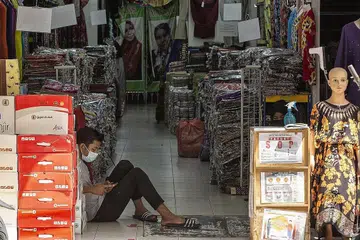 TUNGGU PELANGGAN: Seorang pekerja bermain dengan telefon bimbitnya sedang beliau menunggu pelanggan dekat Jalan Tuanku Abdul Rahman di Kuala Lumpur, minggu lalu. Kuasa membeli golongan bawahan teruk terjejas tahun ini menambah sengsara semasa perayaan Aidilfitri tahun ini. - Foto EPA-EFE