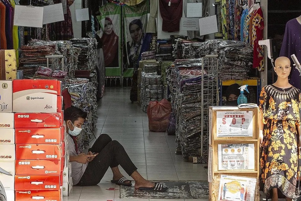 TUNGGU PELANGGAN: Seorang pekerja bermain dengan telefon bimbitnya sedang beliau menunggu pelanggan dekat Jalan Tuanku Abdul Rahman di Kuala Lumpur, minggu lalu. Kuasa membeli golongan bawahan teruk terjejas tahun ini menambah sengsara semasa perayaan Aidilfitri tahun ini. - Foto EPA-EFE