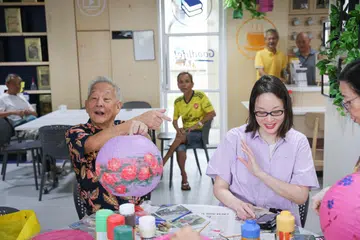 TUNJUK HASIL KARYA: Calon Presiden, Encik Ng Kok Song (kiri), menunjukkan karya seni tunangnya, Cik Sybil Lau, semasa mengunjungi dapur perkhidmatan sosial dan masyarakat, GoodLife! Makan.