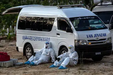 AMAT RENDAH: Pekerja kesihatan kepenatan selepas menguruskan pengebumian korban Covid-19 di Kuala Lumpur pada 22 Mei. Kes harian Covid-19 Malaysia melebihi 6,000 beberapa hari, sedang hanya 7.6 juta daripada 26.7 juta penduduk negara itu telah mendaftar bagi vaksin virus tersebut - "amat rendah" ujar kerajaan. - Foto EPA-EFE