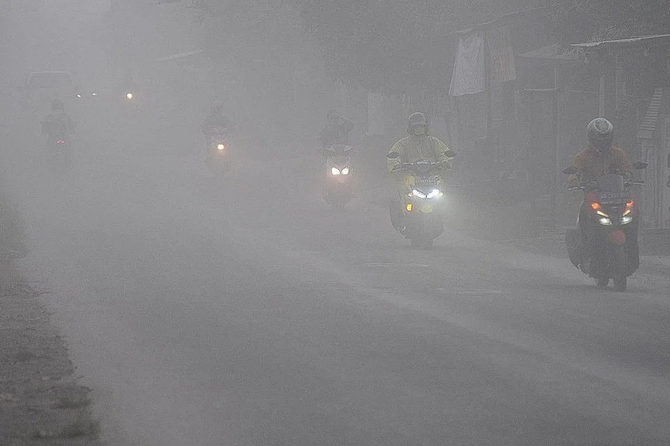 Penunggang motosikal melalui jalan yang kabur dek abu dari Gunung Merapi di Boyolali, wilayah Jawa Tengah, Indonesia. - Foto REUTERS