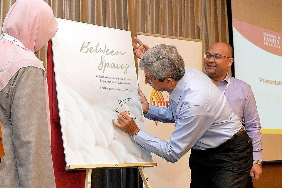 SIMPOSIUM AMALAN KELUARGA PPIS FTI: Dr Yaacob Ibrahim melancarkan buku 'Between Spaces' semasa Simposium Amalan Keluarga PPIS semalam. Memerhatikan ialah Presiden PPIS, Cik Rahayu Mohamad (kiri) dan CEO PPIS, Encik Mohd Ali Mahmood (kanan). - Foto KHALID BABA