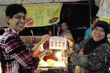 TUMPUAN RAMAI: AP GRC Marine Parade Profesor Madya Dr Fatimah Lateef (kiri) berkata, bazar Geylang Serai masih mampu menarik ramai pengunjung.