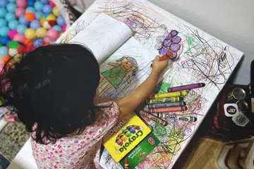 MEJA BELAJAR: Anak penulis kelihatan melukis dengan krayon di meja belajarnya yang dibalut dengan kertas.