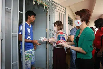 BAWA KECERIAAN: Mayor Daerah South West Low Yen Ling (kanan) dan Penasihat Akar Umbi Hong Kah North Dr Amy Khor (tengah) mengagihkan bungkusan roti kepada seorang penduduk di blok sewa di Hong Kah North kelmarin. - Foto MAJLIS PEMBANGUNAN MASYARAKAT SOUTH WEST
