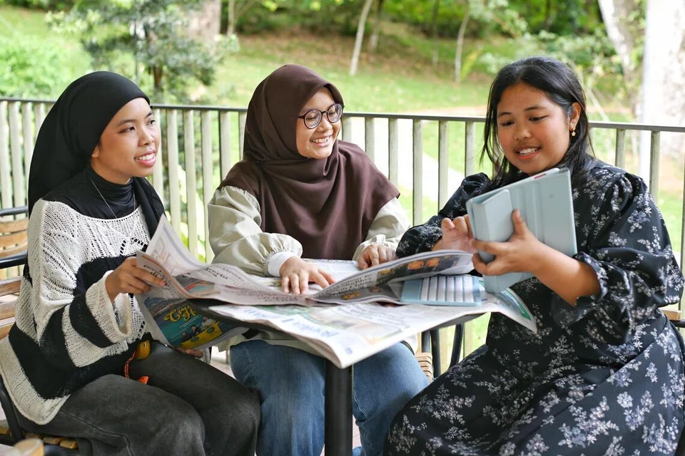 Cik Hanisah Mohamad Ibrahim (tengah) berbincang tentang artikel BH bersama rakan-rakan sekampusnya yang juga anggota Persatuan Bahasa Melayu NUS (PBMUKS), Cik Iffah Munirah Marwan (kiri) dan Cik Reyna Sofyan.