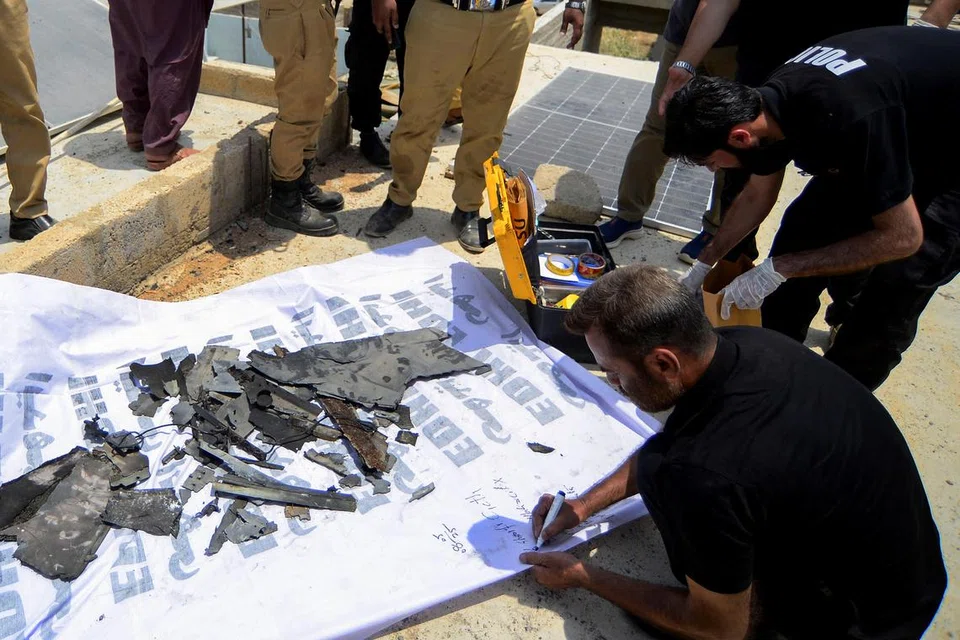 Seorang anggota Unit Tempat Kejadian Jenayah (CSU) memeriksa serpihan yang didakwa sebagai dron selepas ia berjaya ditembak jatuh di kawasan pinggir Karachi, Pakistan pada 8 Mei 2025.