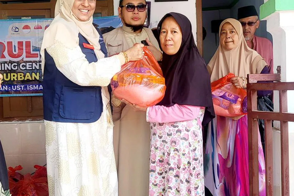 Ustazah Hamidunnisah Mohd Hussein (kiri), isteri Ustaz Ismail Ahmat (tengah), mengagihkan daging korban kepada penerima di Yayasan Anak-anak Yatim di Al-Mabrur di desa Keraksaan, Probolinggo, Jawa Timur, Indonesia, pada tahun 2023.   
