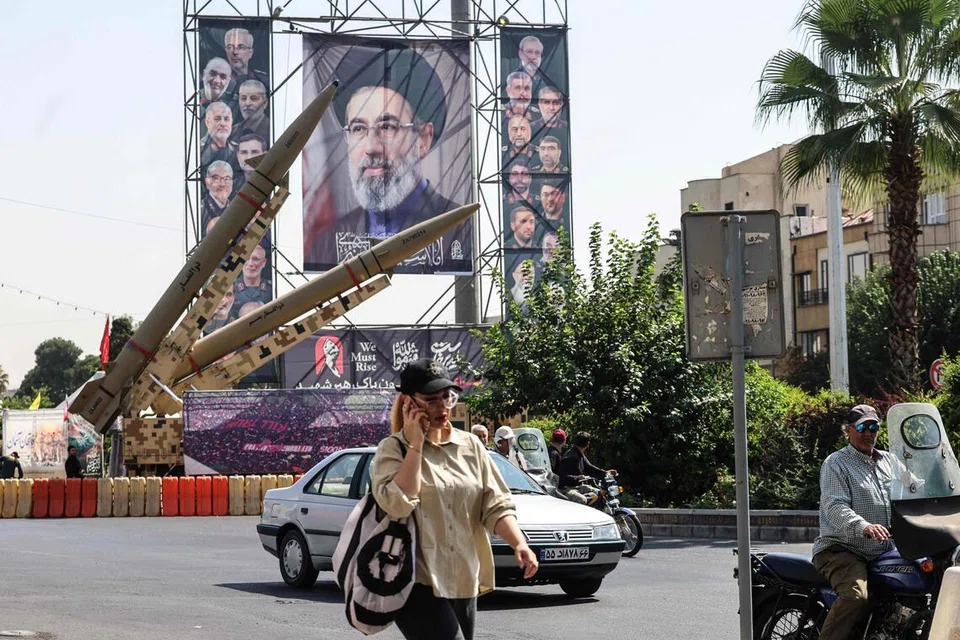 Seorang wanita Iran berjalan melewati peluru berpandu Zolfaghar buatan Iran yang dipamerkan bersebelahan potret besar Pemimpin Tertinggi Iran, Mojtaba Khamenei, di Dataran Baharestan, Tehran, pada 28 September 2026. Ketegangan antara Teheran dengan Washington kekal tinggi selepas rundingan tidak langsung kedua-dua pihak gagal mencapai kemajuan. 