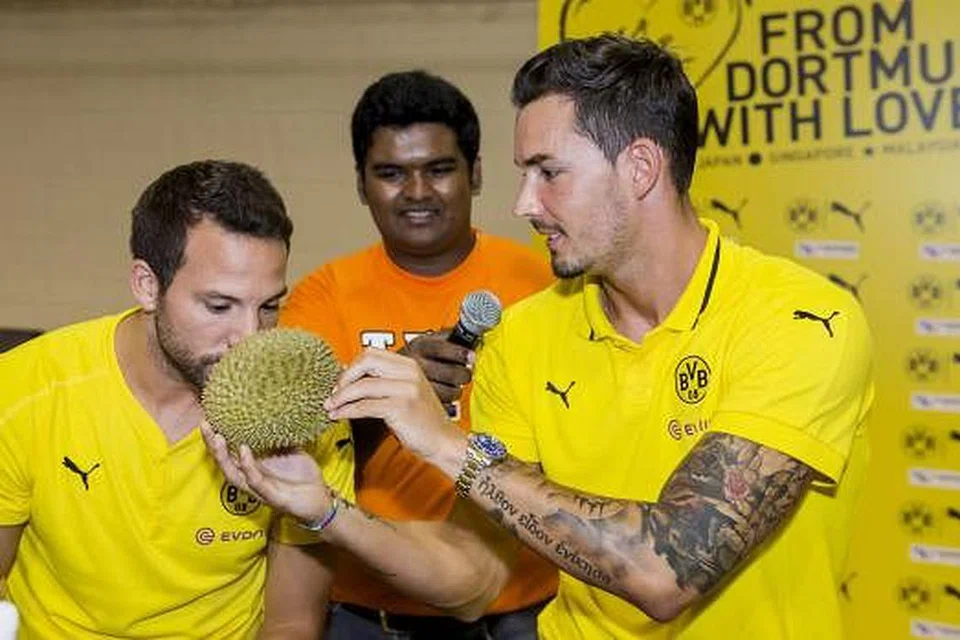 SEDAP TAK?: Penjaga gawang Borussia Dortmund, Roman Burki (kanan) kelihatan megajukan sebiji durian kepada pemain tengahnya, Gonzalo Castro (kiri), untuk dihidu. - Foto POLITEKNIK NANYANG