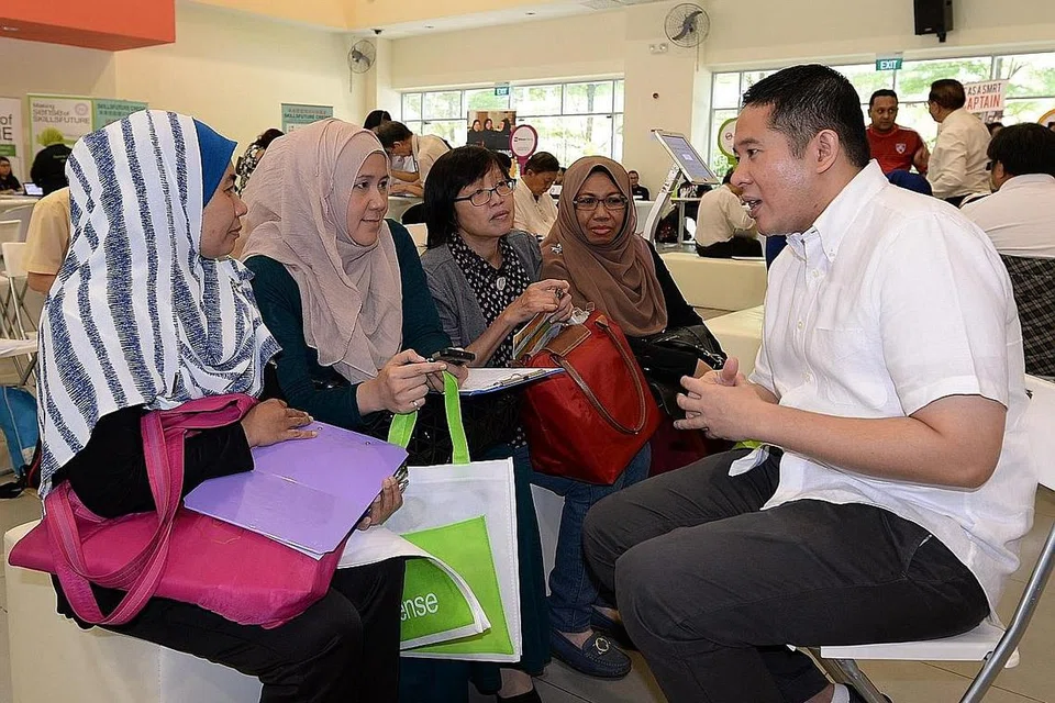 BERSIKAP POSITIF: Beberapa pemohon termasuk Cik Marfo'ah (dua dari kiri) yakin akan mendapat kerja menerusi Pameran Kerjaya di Woodlands ini. Mereka mengongsi keprihatinan kepada Encik Amrin semalam.