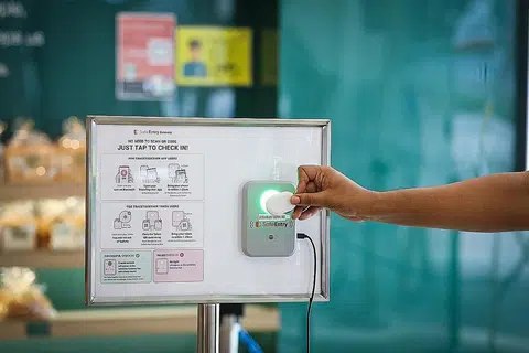 LEBIH MUDAH DAN PANTAS: Untuk daftar masuk ditempat guna Kotak Pintu Masuk SafeEntry, pengunjung boleh menggunakan aplikasi atau token TraceTogether dan menyentuh alat mereka pada kotak pintu masuk, yang saiznya lebih besar sedikit daripada telefon bimbit. - Foto ZAOBAO