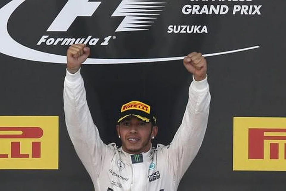 AKSI JUARA: Hamilton mengangkat kededua tangannya selepas muncul sebagai juara dalam Grand Prix Jepun kelmarin. - Foto REUTERS