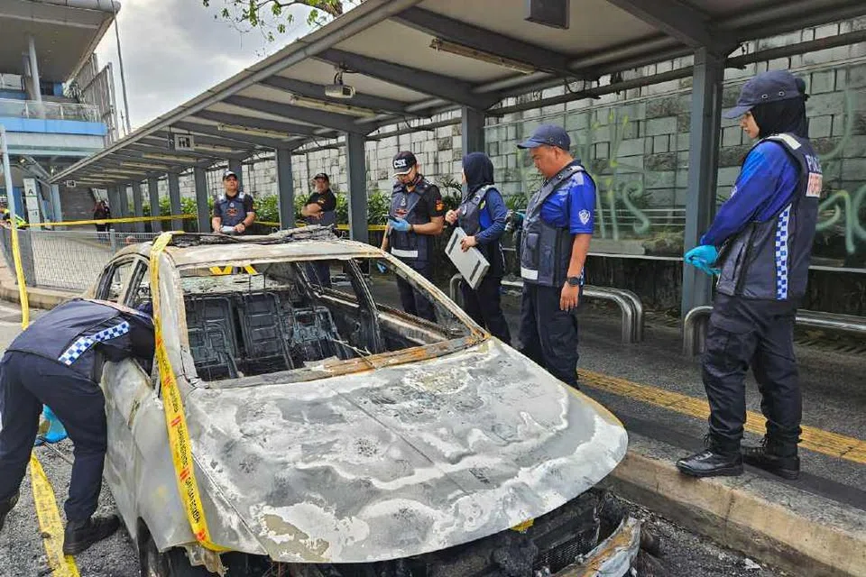 Anggota polis memeriksa kereta polis bantuan yang dibakar seorang lelaki berhampiran Stesen Transit Aliran Massa (MRT) Mutiara Damansara, di Petaling Jaya, Selangor pada 15 Februari.