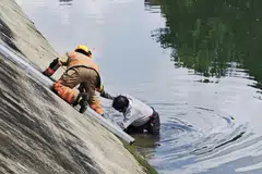 SELAMAT: Seorang lelaki kelihatan ditarik keluar dari terusan oleh seorang pegawai SCDF.