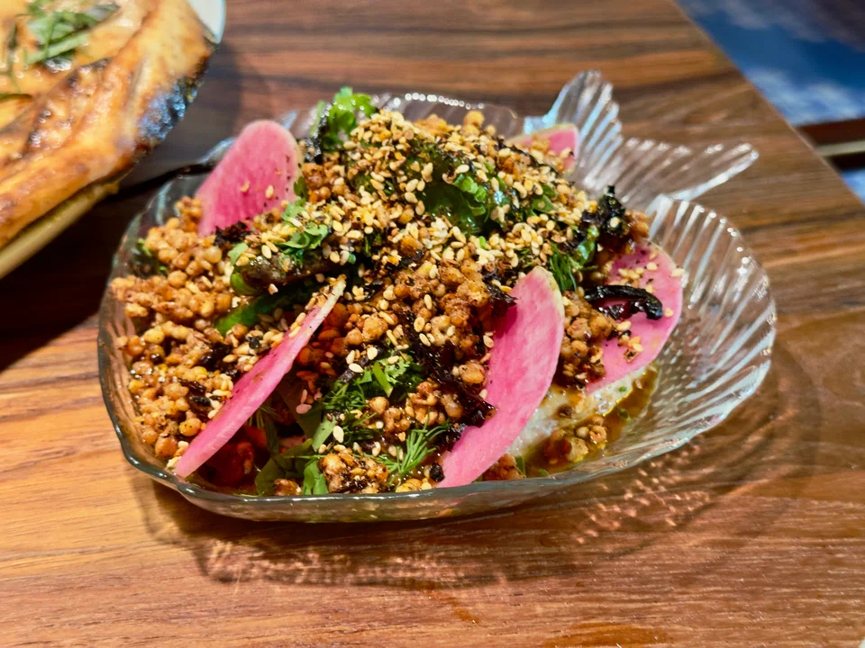 Creamy taramasalata lies under crunchy buckwheat and radish slices.