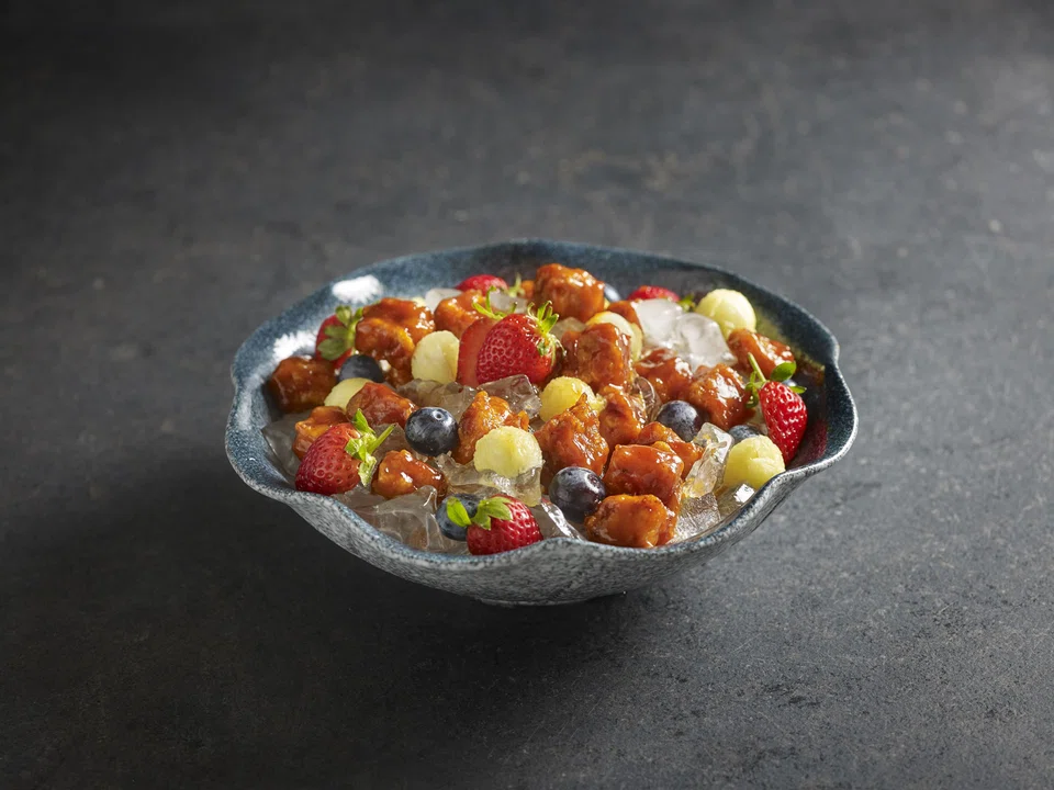 Icy nuggets of sweet sour pork are presented on ice with mixed fruit.
