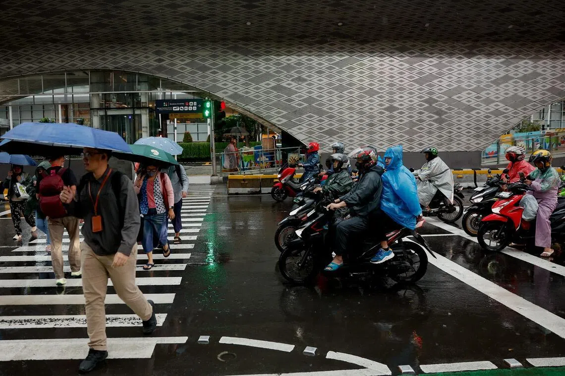 epa12644057 People holding umbrellas cross the street in the rain in Jakarta, Indonesia, 12 January 2025. Indonesia’s Meteorology, Climatology, and Geophysics Agency (BMKG) issued an early warning of extreme weather across the country, including heavy rainfall and potential high waves in several water areas.  EPA/MAST IRHAM