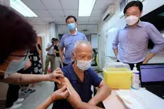 DPM Lawrence Wong (right) and Minister for Health Ong Ye Kung (centre back) at the mobile vaccination team at Nee Soon Central Zone 3 Residents’ Committee, on June 27, 2022. 