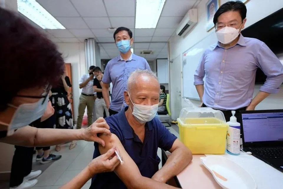 DPM Lawrence Wong (right) and Minister for Health Ong Ye Kung (centre back) at the mobile vaccination team at Nee Soon Central Zone 3 Residents’ Committee, on June 27, 2022. 
