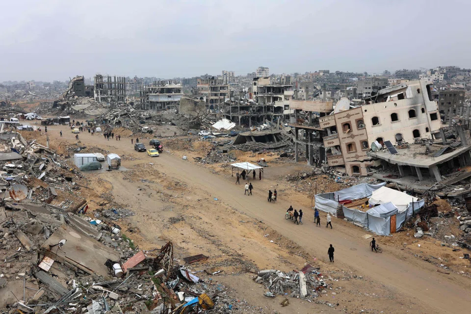 People walk amid collapsed buildings along Saftawi street in Jabalia in the northern Gaza Strip on Feb 5, 2025 during a ceasefire deal in the war between Israel and Hamas. Palestinian militant group Hamas lashed out at President Donald Trump's shock proposal for the United States to take over the Gaza Strip and resettle its people in other countries, seemingly whether they want to leave or not. 