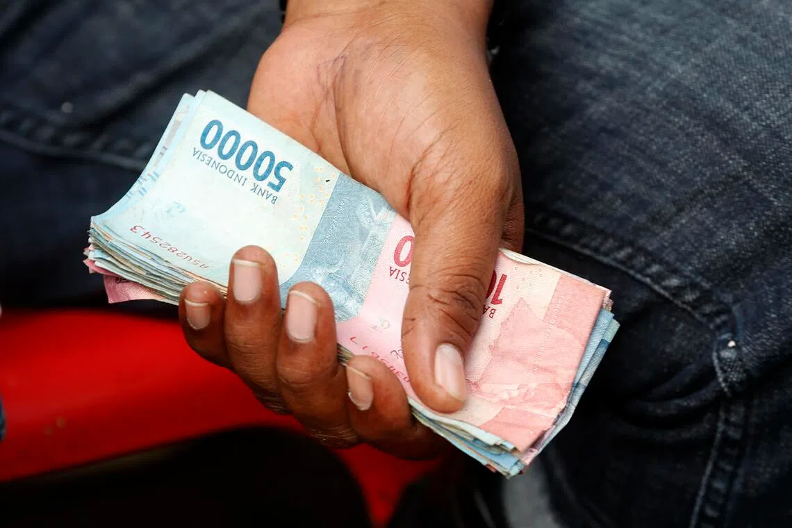 epa12521998 A trader holds Indonesian banknotes during a transaction at a fish auction market in Lampulo, Banda Aceh, Indonesia, 13 November 2025. The government, through the Ministry of Finance, is finalizing plans to simplify, or redenominate, the rupiah by 2027. The 1,000-rupiah note will be worth 1 rupiah. Redenomination involves removing several zeros from the value of money or goods, simplifying the recording of the value of goods, services, and money.  EPA/HOTLI SIMANJUNTAK