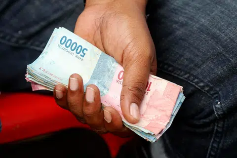epa12521998 A trader holds Indonesian banknotes during a transaction at a fish auction market in Lampulo, Banda Aceh, Indonesia, 13 November 2025. The government, through the Ministry of Finance, is finalizing plans to simplify, or redenominate, the rupiah by 2027. The 1,000-rupiah note will be worth 1 rupiah. Redenomination involves removing several zeros from the value of money or goods, simplifying the recording of the value of goods, services, and money.  EPA/HOTLI SIMANJUNTAK